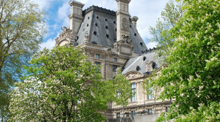 Palais historique entouré d'arbres en fleurs, ciel bleu.