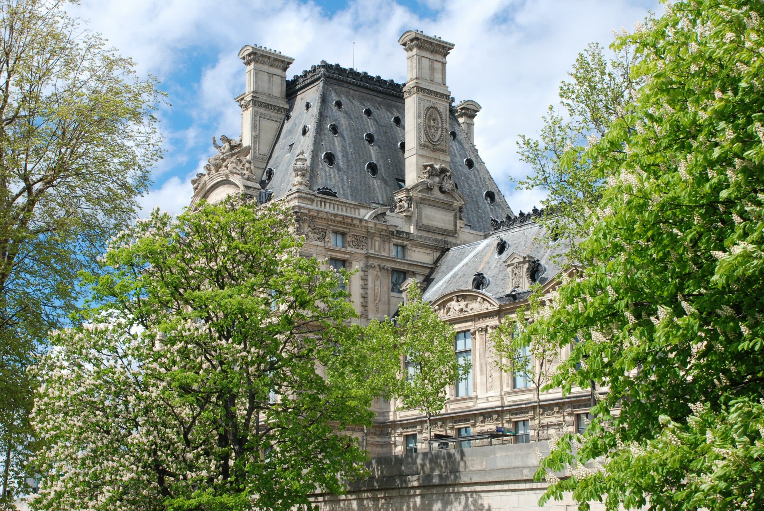 Palais historique entouré d'arbres en fleurs, ciel bleu.