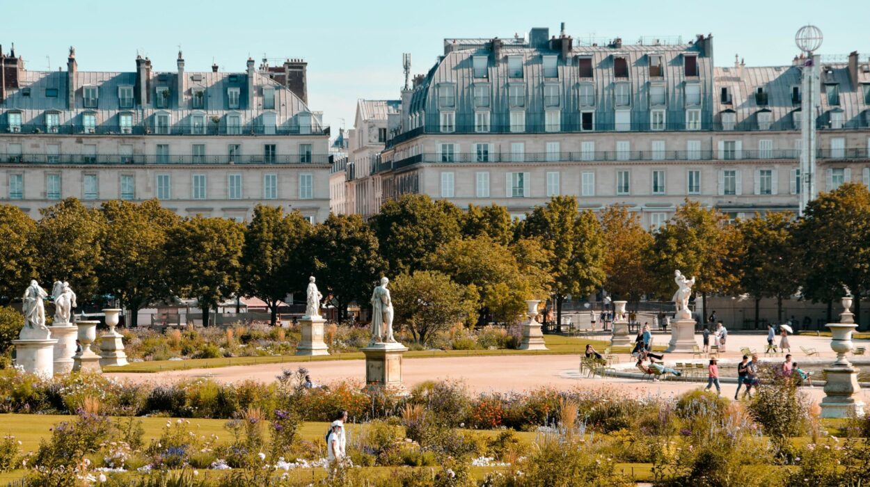Jardin parisien ensoleillé avec statues et passants.