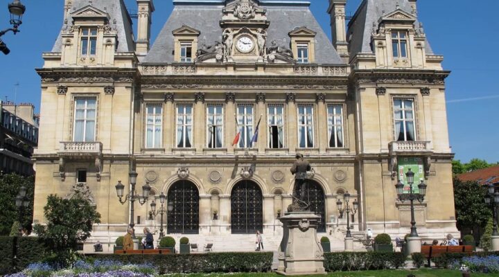 Hôtel de ville historique avec jardin fleuri en été.