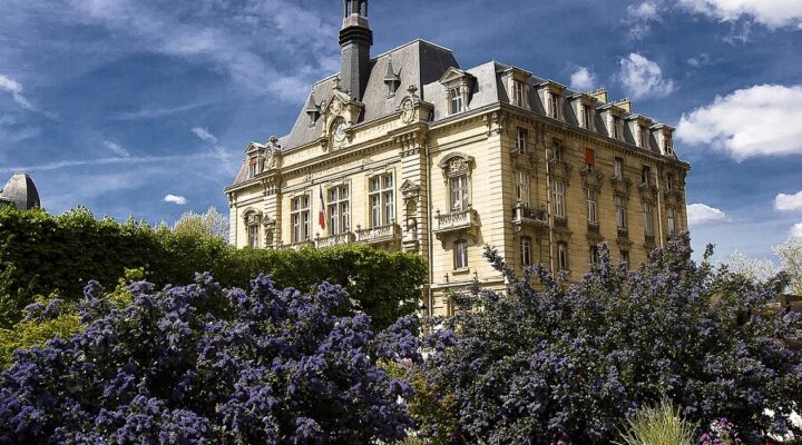 Hôtel de ville entouré de fleurs violettes sous ciel bleu.