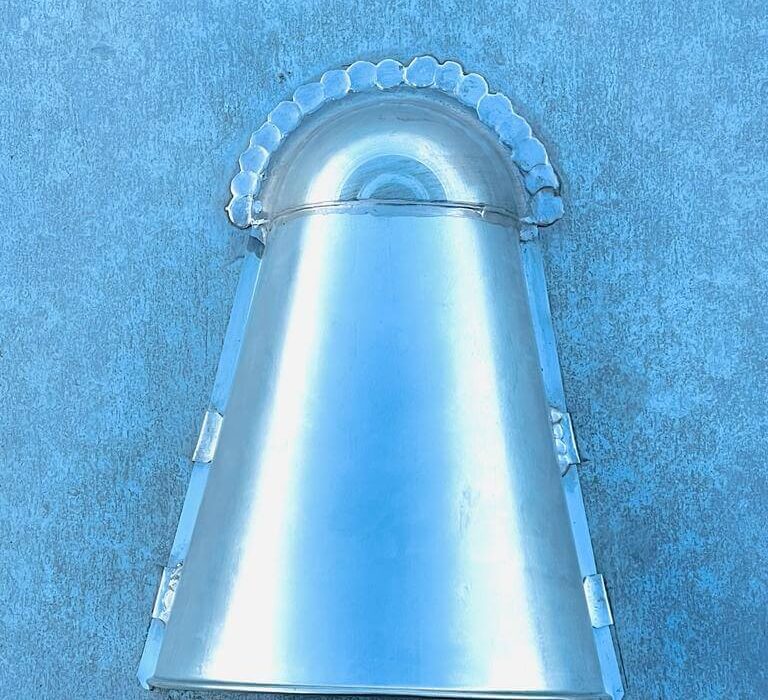 Cloche en métal argenté sur fond bleu.