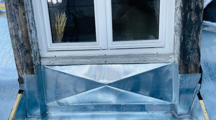 Zinc en façade, fenêtre boisée, style rustique.