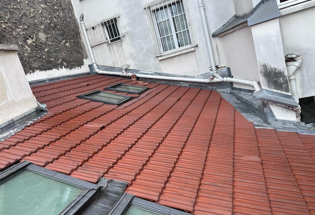 Toit en tuiles rouges avec fenêtres de toit.