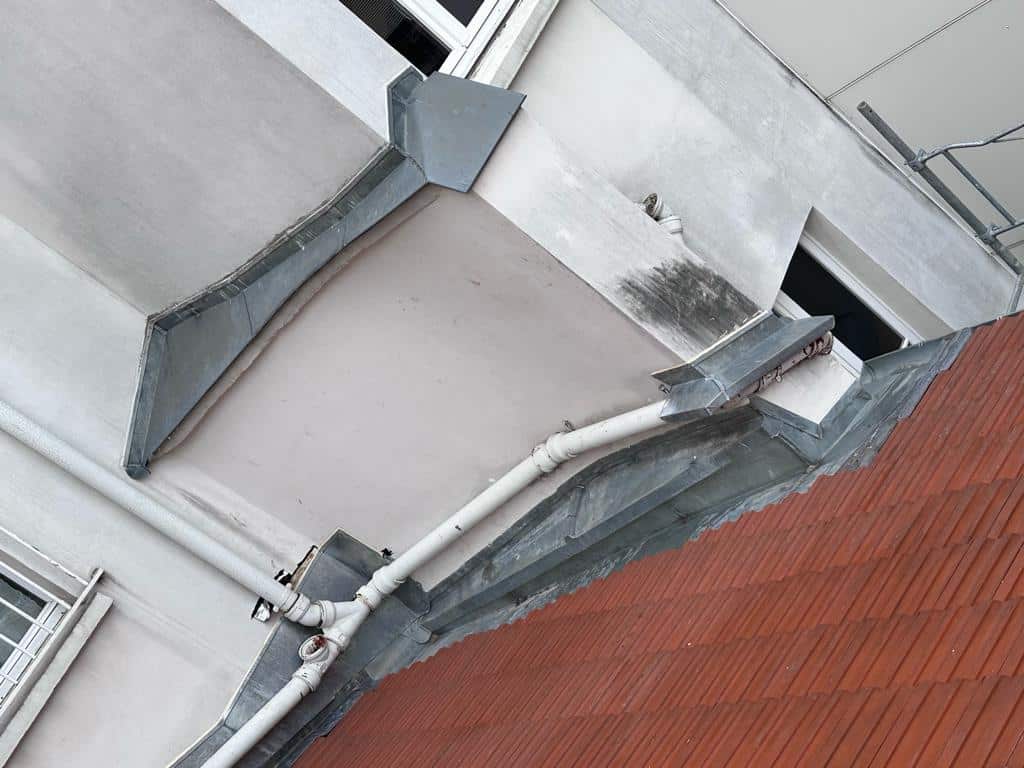 Façade immeuble avec toiture et gouttières.