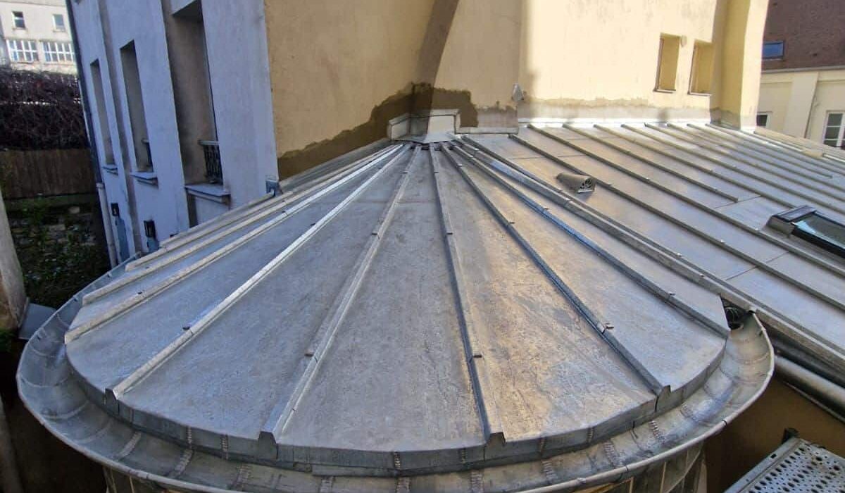 Toit en dôme métallique entre immeubles urbains.