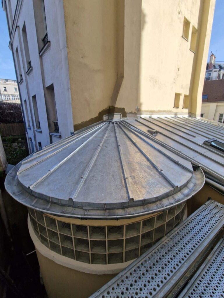 Toit en dôme métallique entre immeubles urbains.