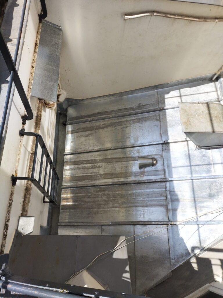 Cage d'escalier en métal éclairée par le soleil.