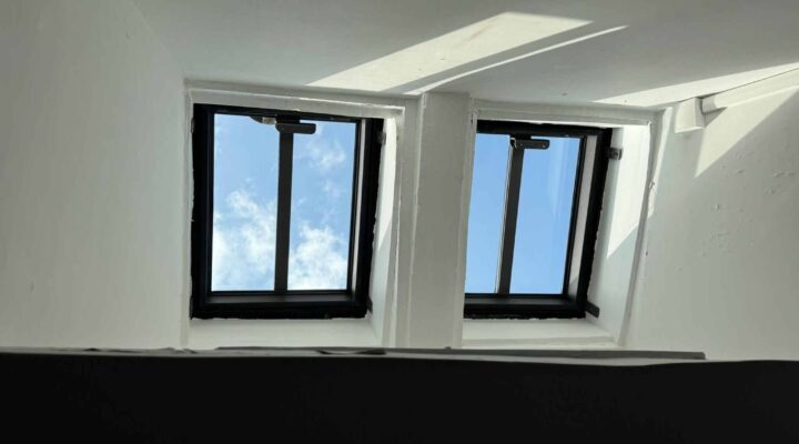 Deux fenêtres de toit ouvertes sur le ciel bleu.